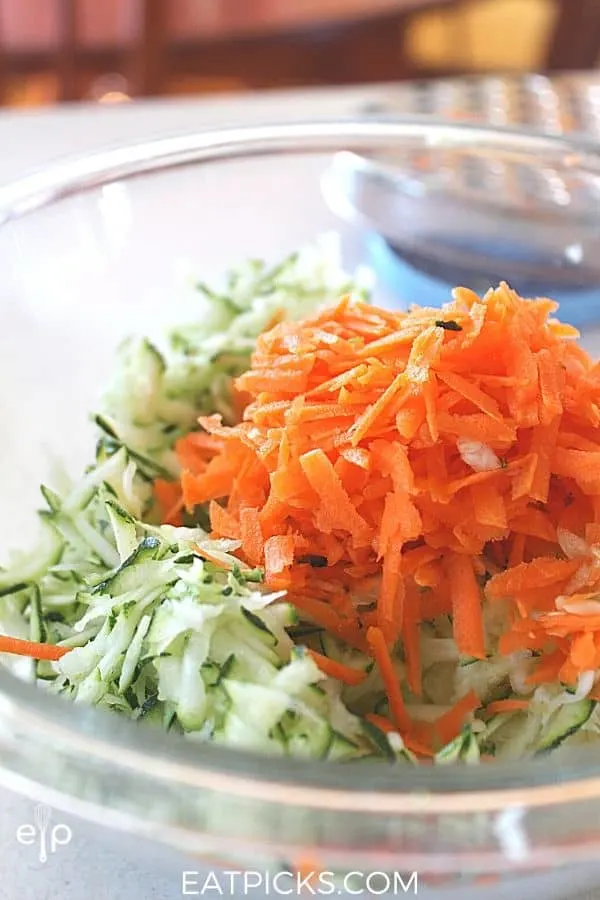 grated zucchini and carrots in a glass mixing bowl