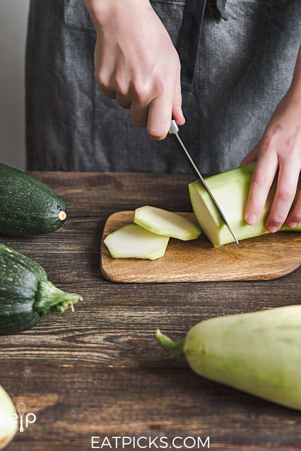 Slicing peeled zucchini on cutting board