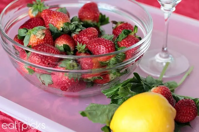 Bowl of fresh Florida Strawberries on tray with glass and lemon