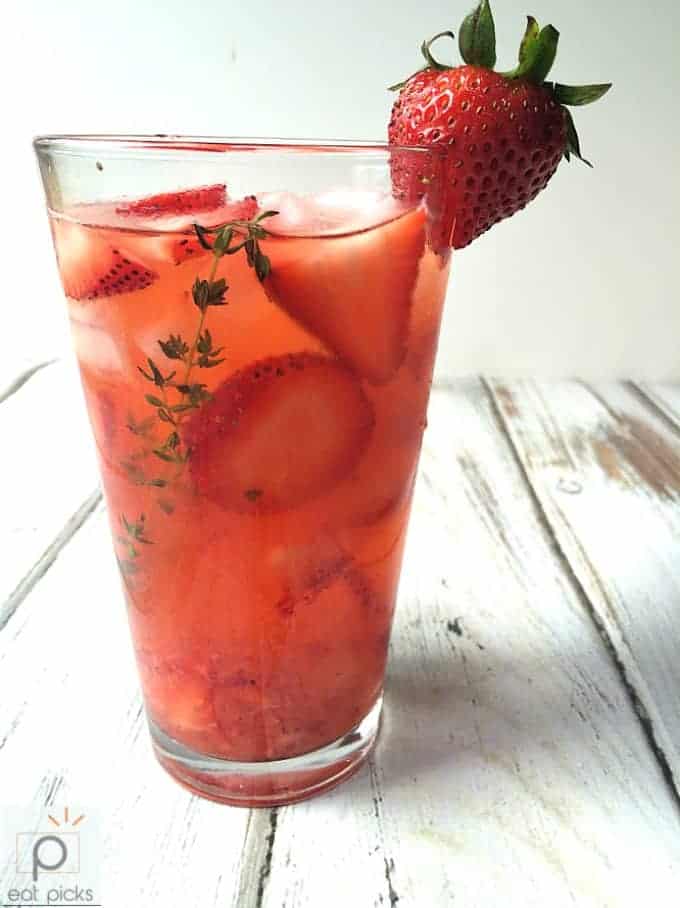 Strawberry lemonade with fresh strawberry garnish and sprig of thyme
