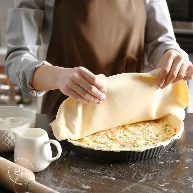 Person placing crust on top of potpie filling