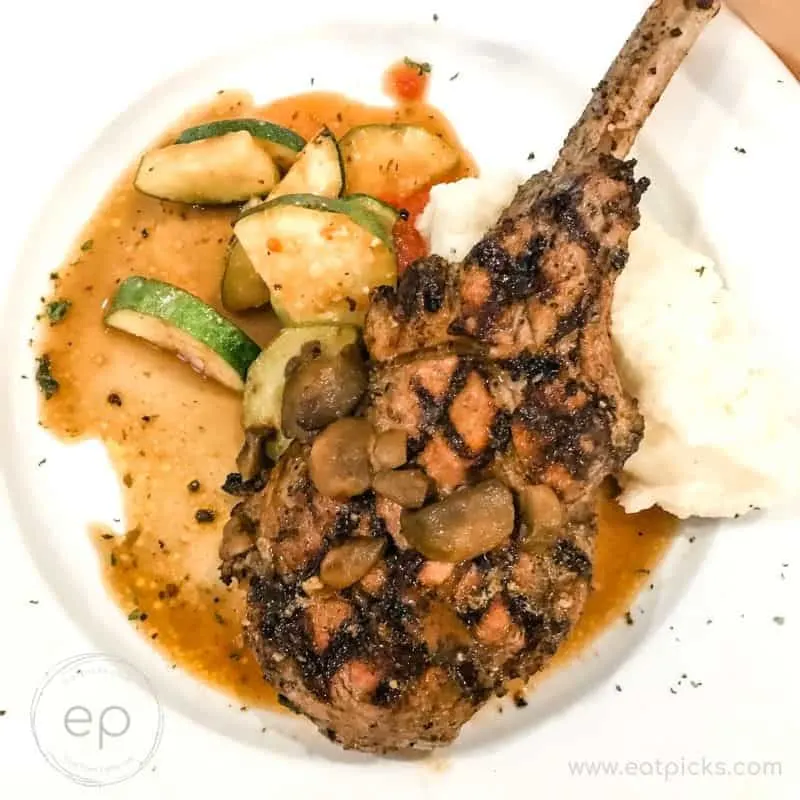 veal chop on plate with potatoes and vegetables