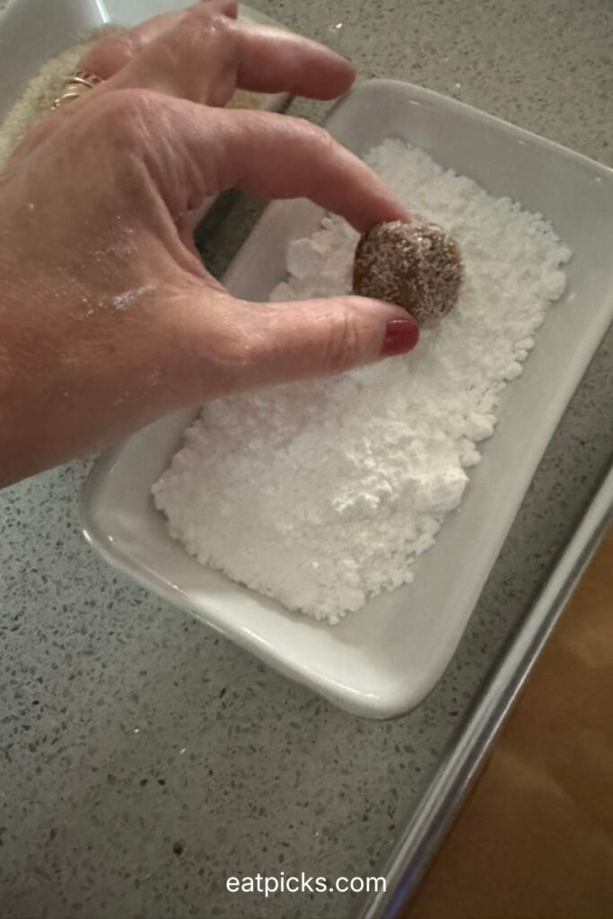 rolling cookie ball in confectioners sugar